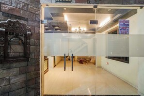 Et hotelreceptionsområde med en lukket dør, en lysekrone og et skilt med hotellets navn og adresse.