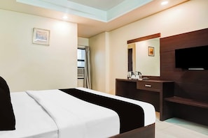 Una habitación de hotel con cama, cómoda, espejo, televisión y ventana con cortinas.