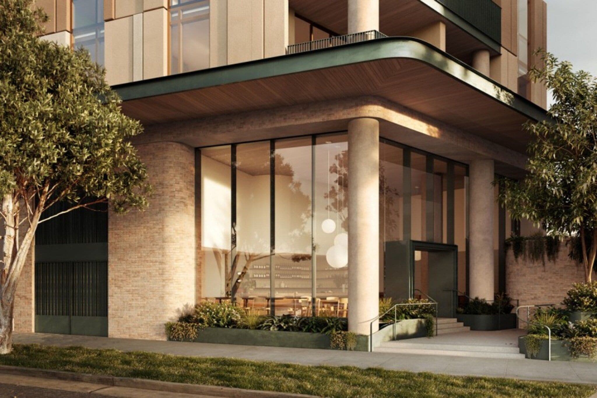 A modern building with large windows, a curved roof, and a well-maintained garden area.