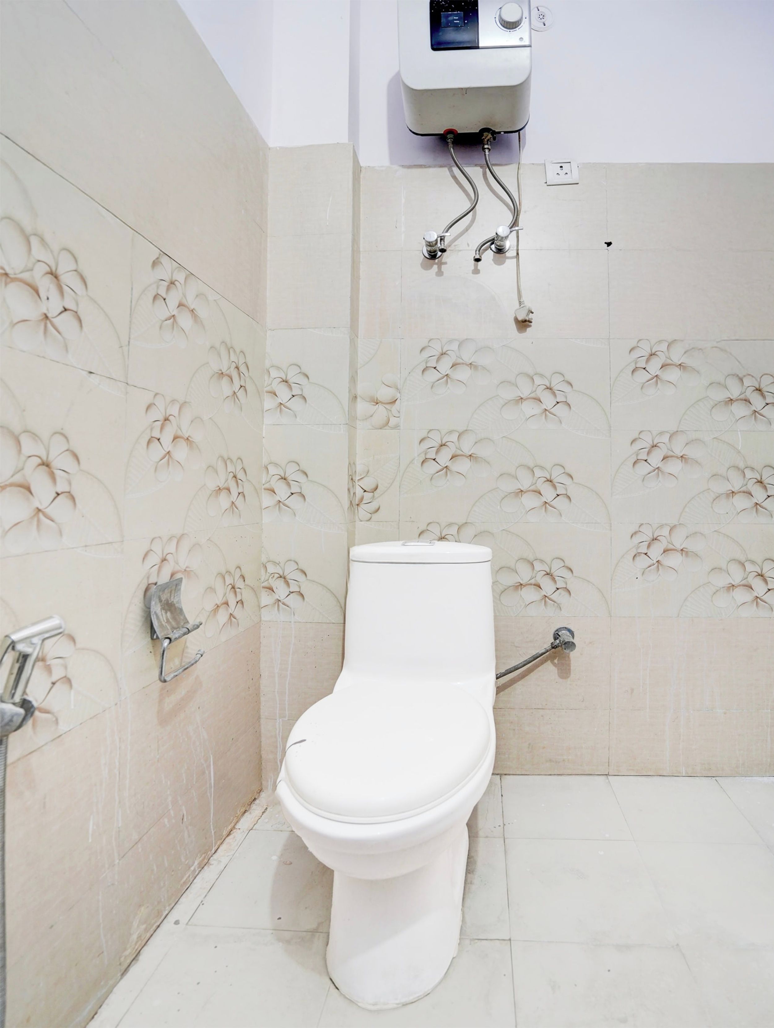 Un baño con inodoro, ducha y calentador de agua instalado en la pared.