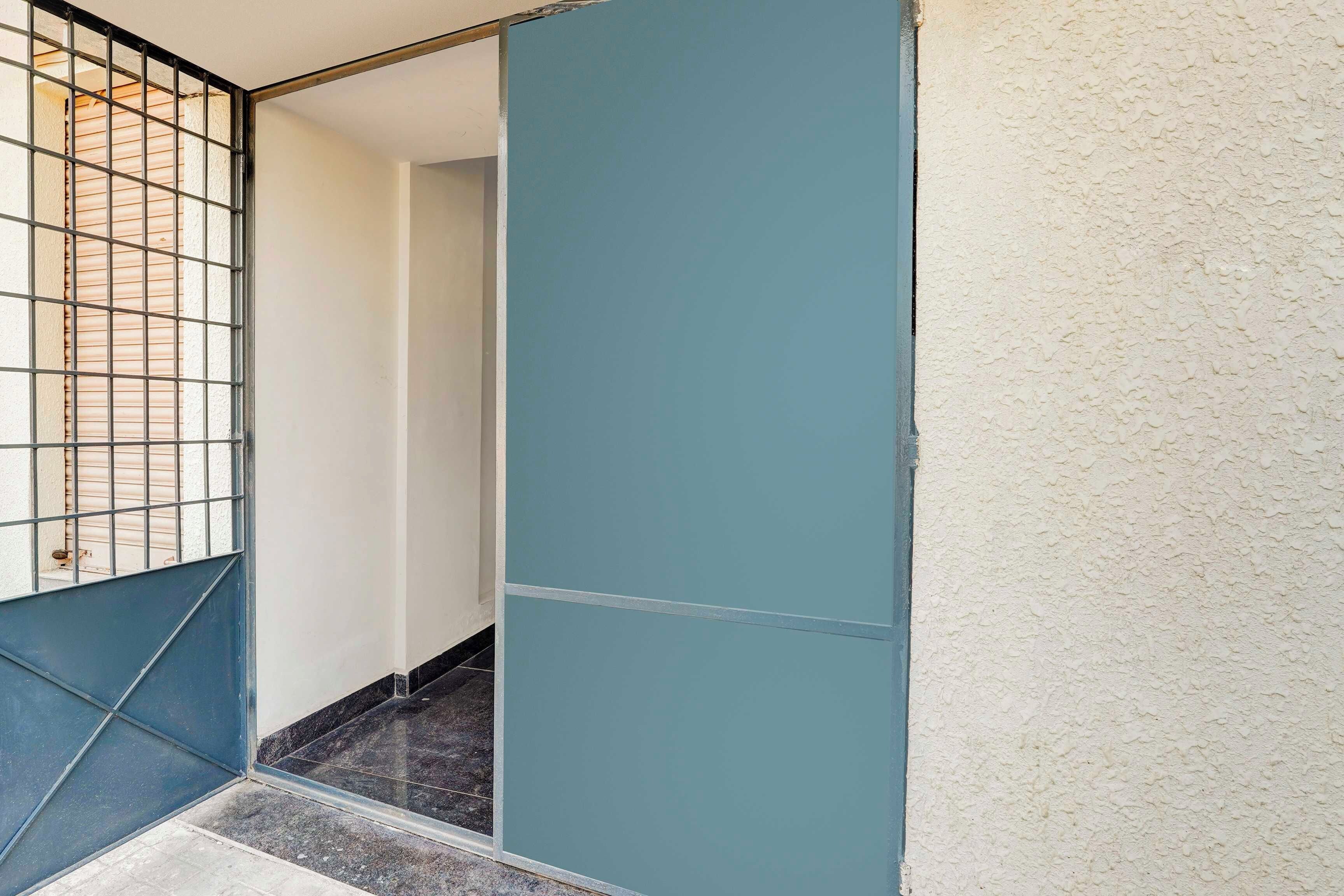 Un pasillo con piso de baldosas, pared azul y una reja de metal.