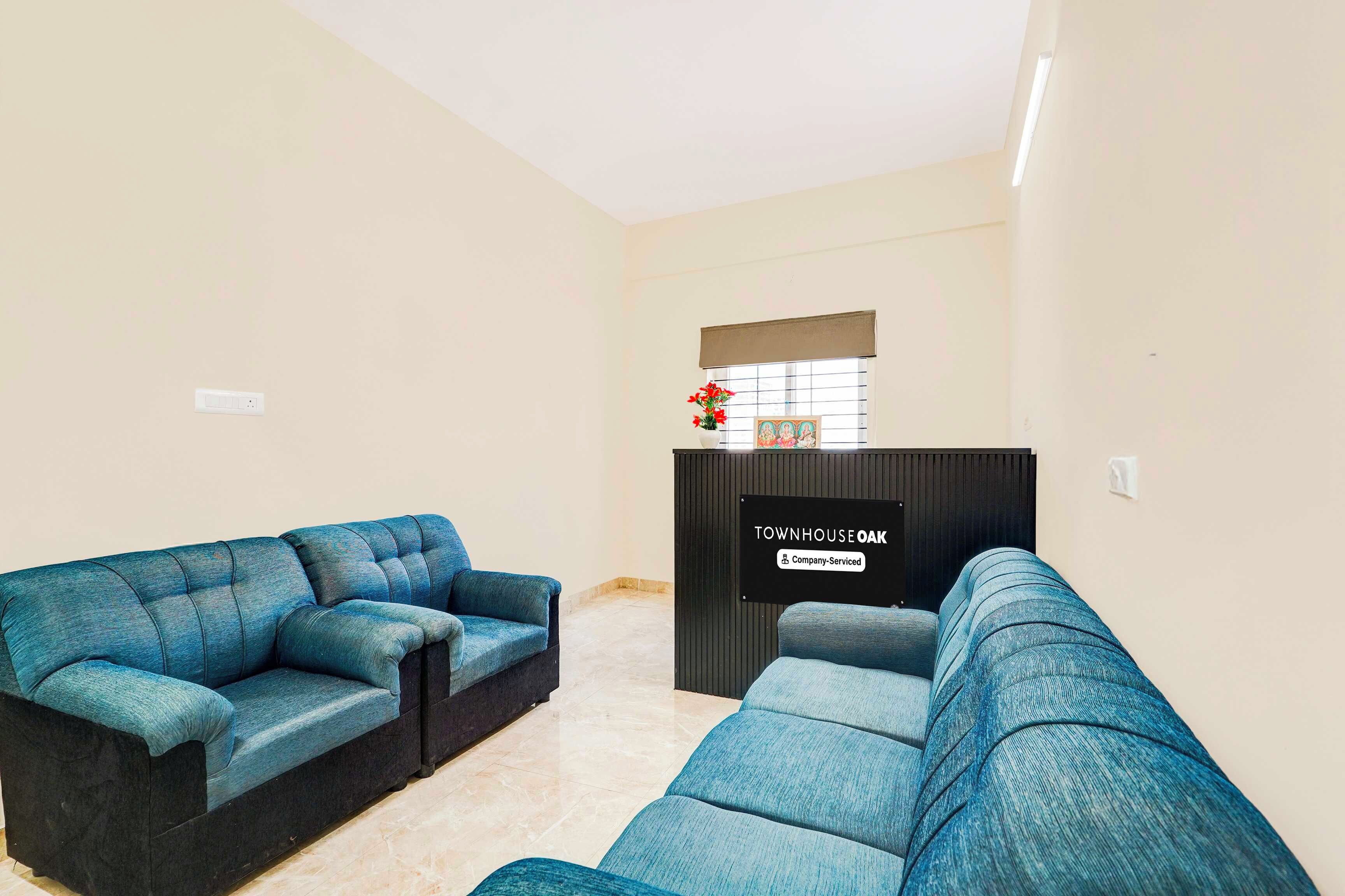 Una sala de estar con dos sofás azules, un mueble de madera oscura y un letrero que indica 'TOWNHOUSE OAK Company Serviced'.