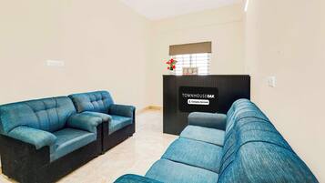 Una sala de estar con dos sofás azules, un mueble de madera oscura y un letrero que indica 'TOWNHOUSE OAK Company Serviced'.