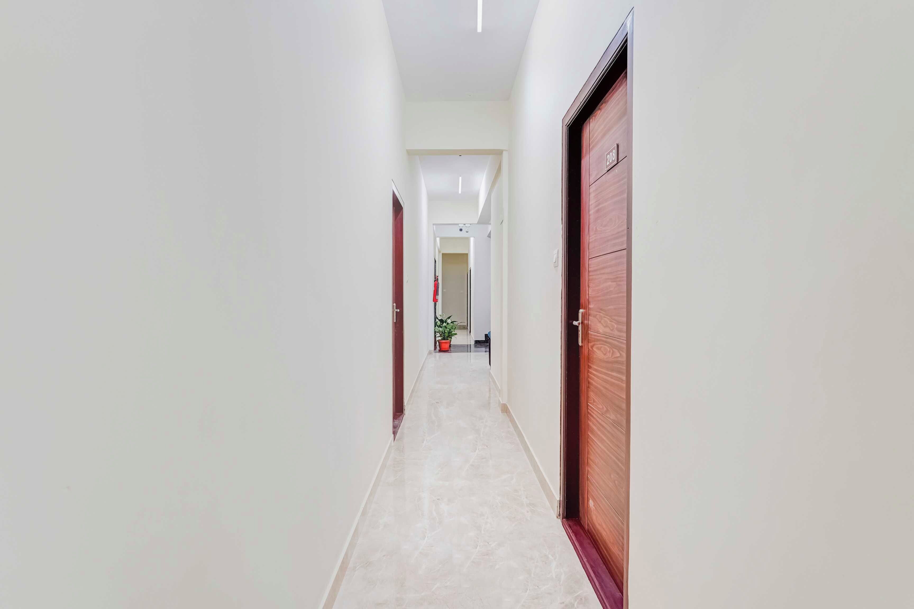 Un pasillo con piso de mármol, paredes blancas y puertas de madera.