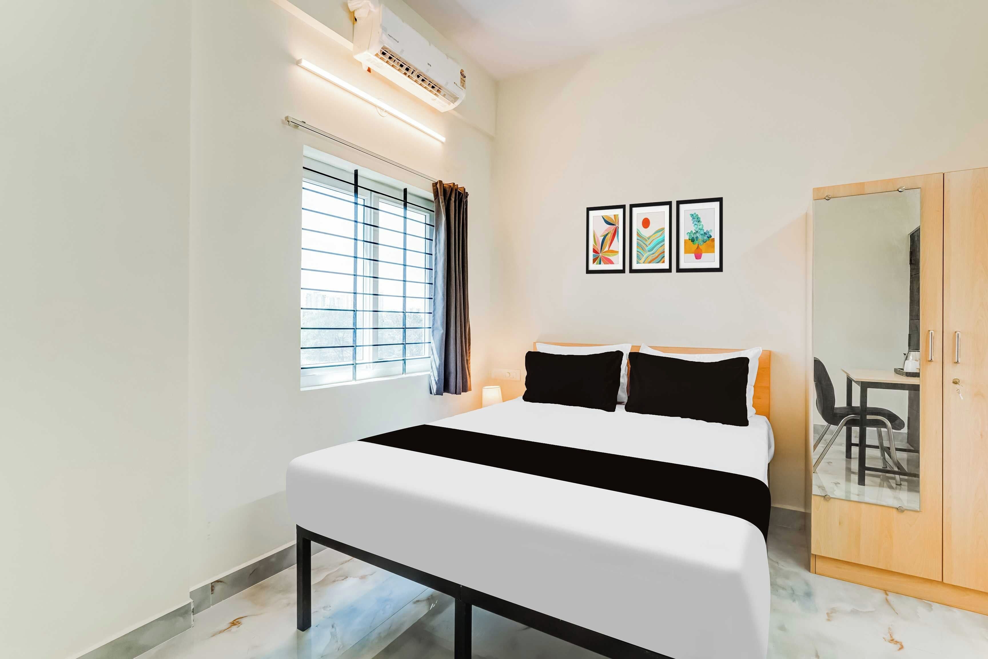 Una habitación de hotel con una cama, una ventana con persianas, un aire acondicionado de pared y un espejo.
