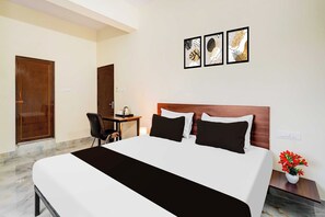 Habitación de hotel con una cama, un escritorio y una silla. Hay tres cuadros en la pared.