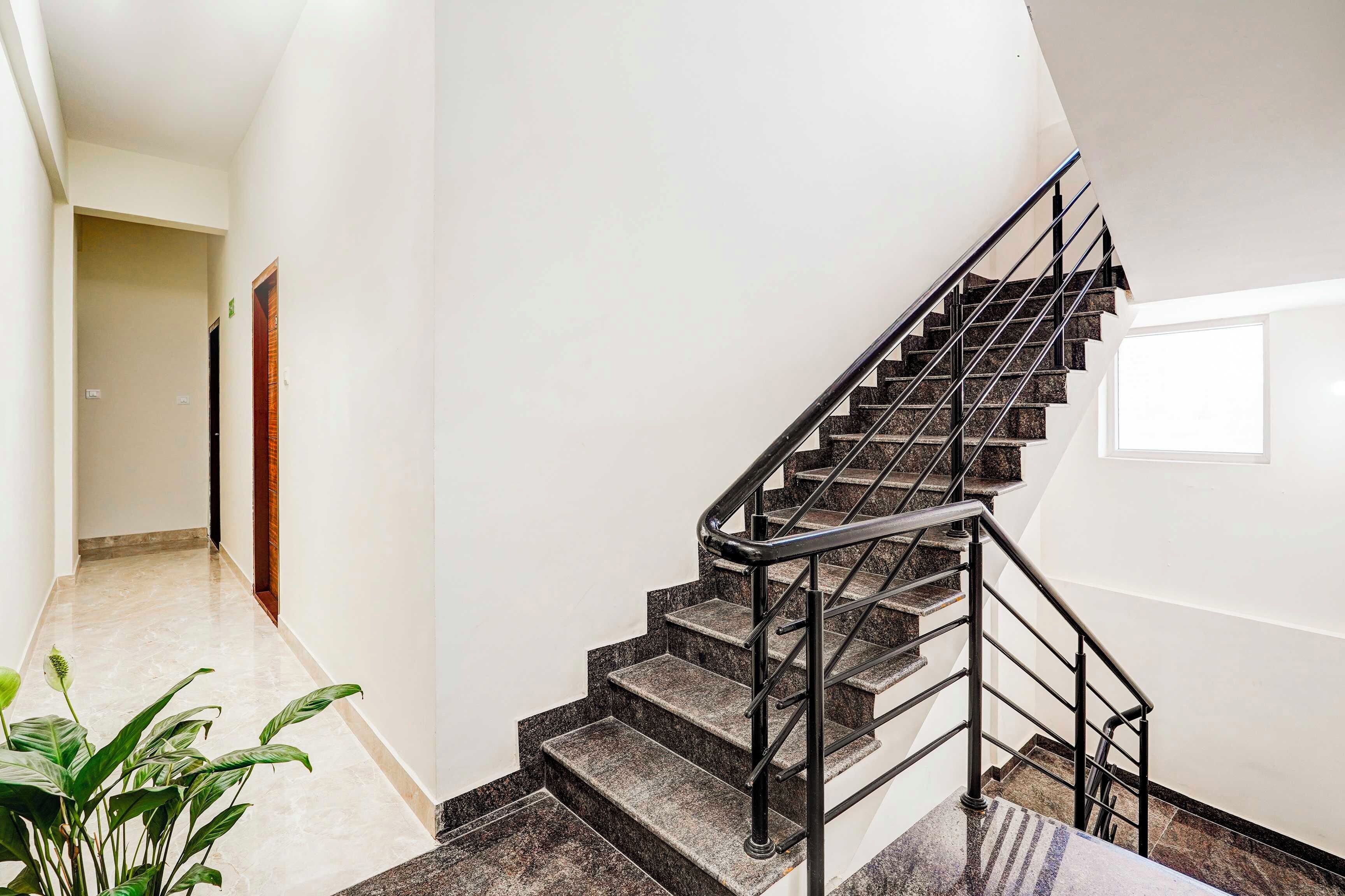 Una escalera moderna con barandilla de metal que lleva a un rellano con una puerta.