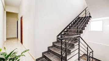 Una escalera moderna con barandilla de metal que lleva a un rellano con una puerta.