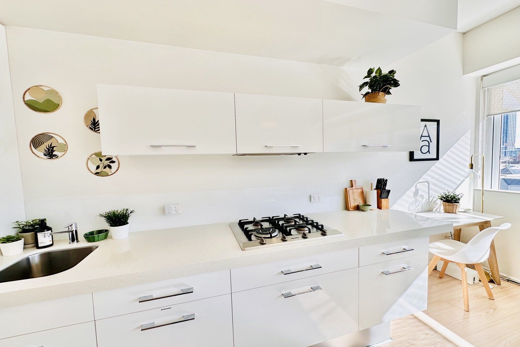 A modern kitchen with white cabinetry, a gas stove, and a dining area with a white table and chair.