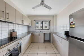Una cocina moderna con horno empotrado, refrigerador de acero inoxidable y ventilador de techo.