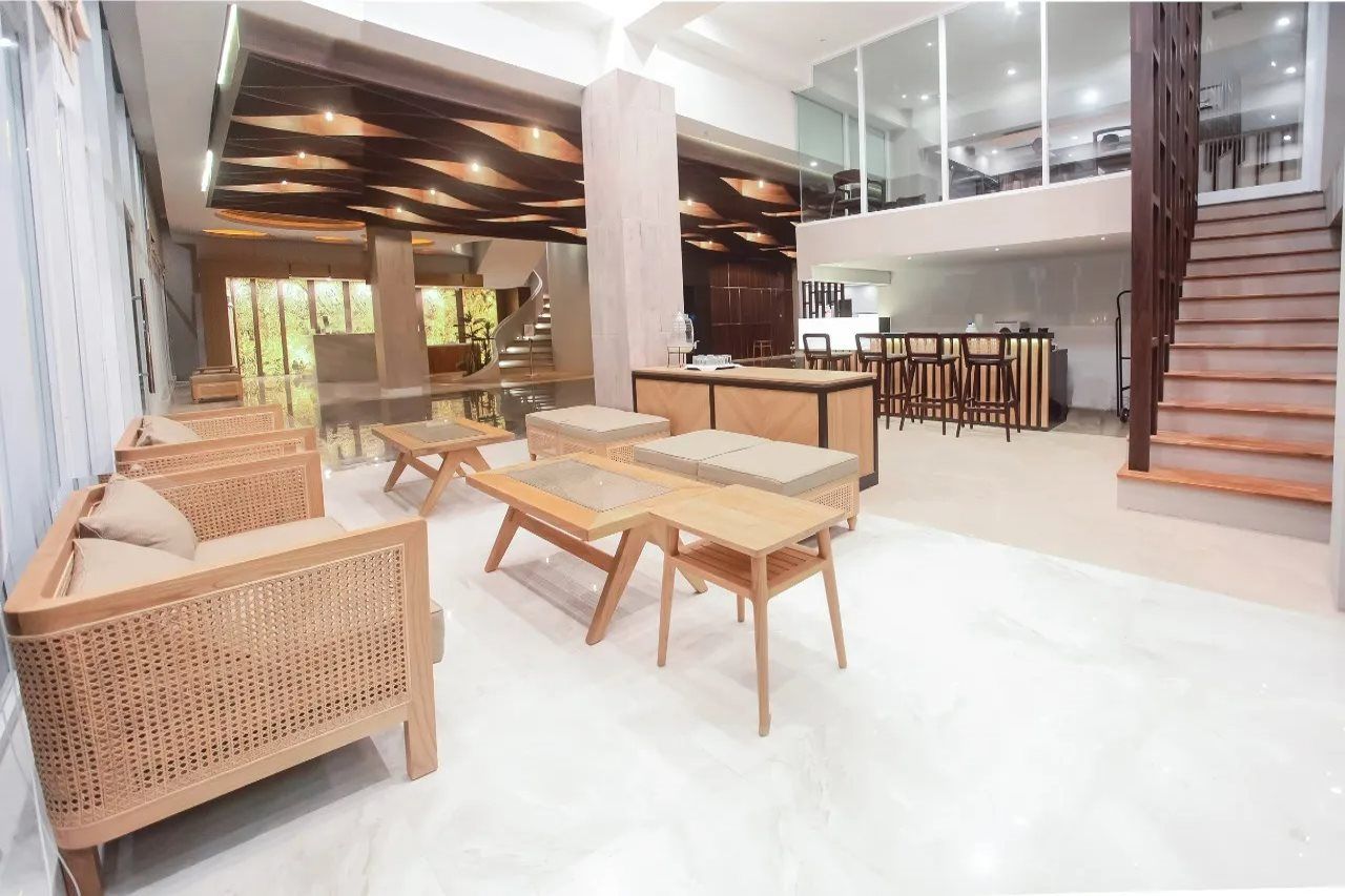 Eine geräumige Lobby mit hoher Decke, einer Treppe und einer Sitzecke mit Holzmöbeln.