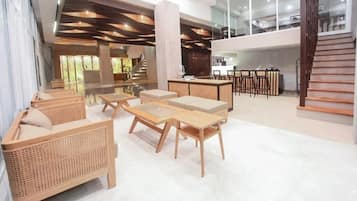Eine geräumige Lobby mit hoher Decke, einer Treppe und einer Sitzecke mit Holzmöbeln.
