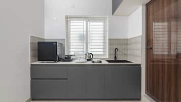 Cocina compacta con refrigerador empotrado, un lavamanos y una ventana sobre la encimera.