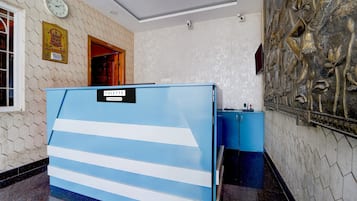 Quarto de hotel com divisória azul, relógio na parede e um objeto decorativo na parede.
