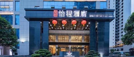 A hotel entrance with a modern facade, illuminated signage, and a well-maintained entrance area.