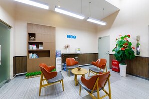 A reception area with a reception desk, a water dispenser, a plant, and seating arrangements. - Echarm Hotel (Shenzhen)