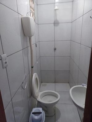 Um banheiro pequeno com azulejos, vaso sanitário, bidê e lixeira.