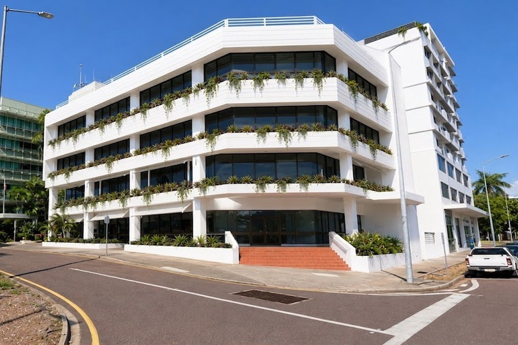A multi-story building with a flat roof, large windows, and a central entrance with steps.