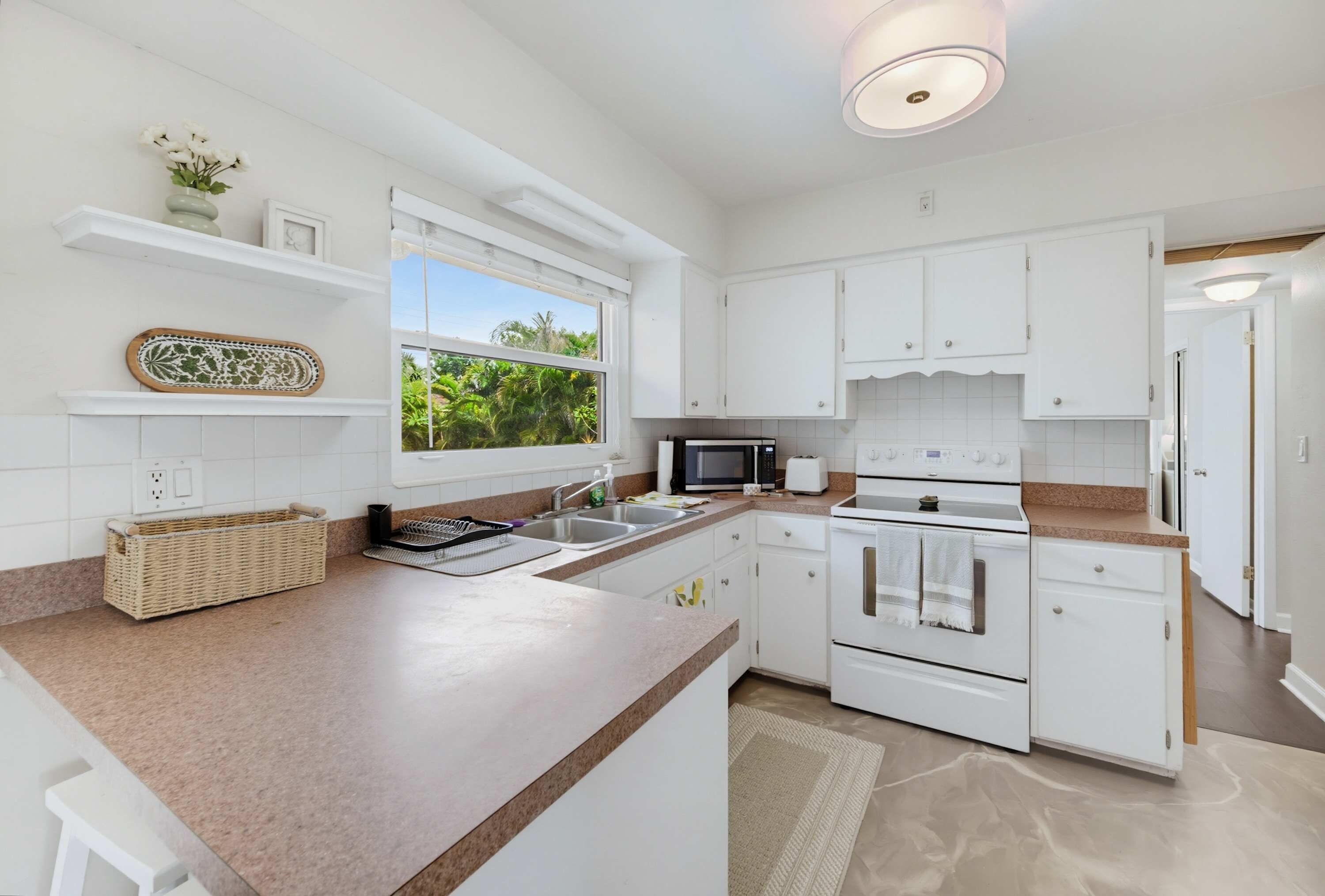 A modern kitchen with white cabinetry, a large island, a microwave, and an oven.