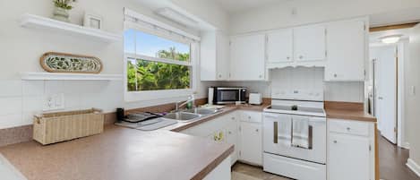 A modern kitchen with white cabinetry, a large island, a microwave, and an oven.