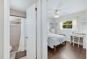 A bedroom with a bed, a desk, a chair, and a window with curtains. - Pet Friendly 2BR Fenced-In near St. Pete Beach (St. Petersburg)