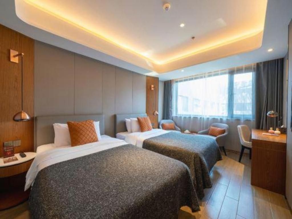 A hotel room with two beds, a desk, and a window with curtains.