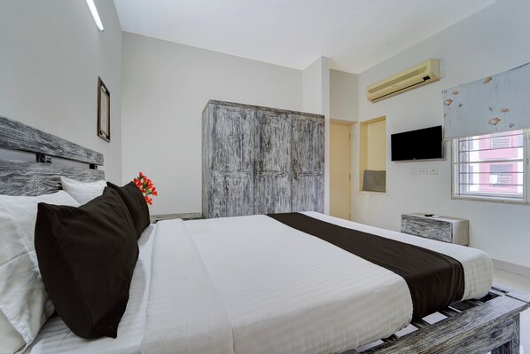 A hotel room with a large bed, a television mounted on the wall, and a window with a view of the outside.
