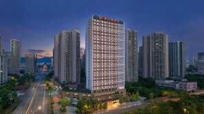 A high-rise hotel with multiple floors, surrounded by other tall buildings, and a road with moving vehicles. - Vienna Hotel (Chongqing)