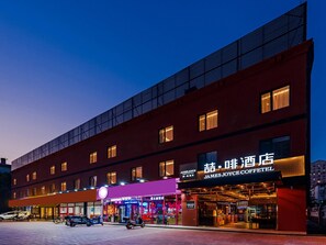 A modern building with a coffee shop named 'James Joyce Coffetel' on the ground floor, featuring a bright sign and a storefront with glass doors. - James Joyce Coffetel (Beijing)