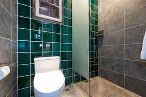 A bathroom with a toilet, green tiles, and a shower area. - James Joyce Coffetel (Beijing)