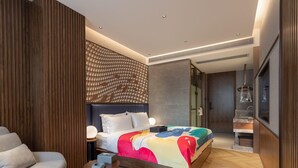 A modern bedroom with a large bed, a seating area with a chair, and a small table. - Zmax Hotels (Shenzhen)