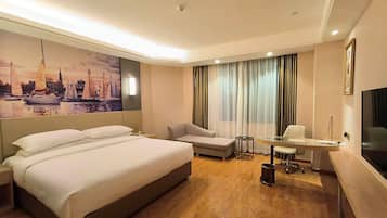 A hotel room with a large bed, a desk, a chair, and a television.