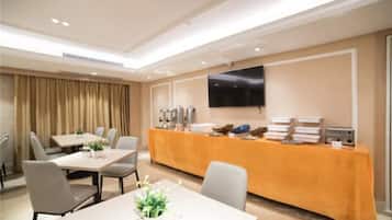 A conference room with a long table, chairs, a buffet table, and a flat-screen TV on the wall.