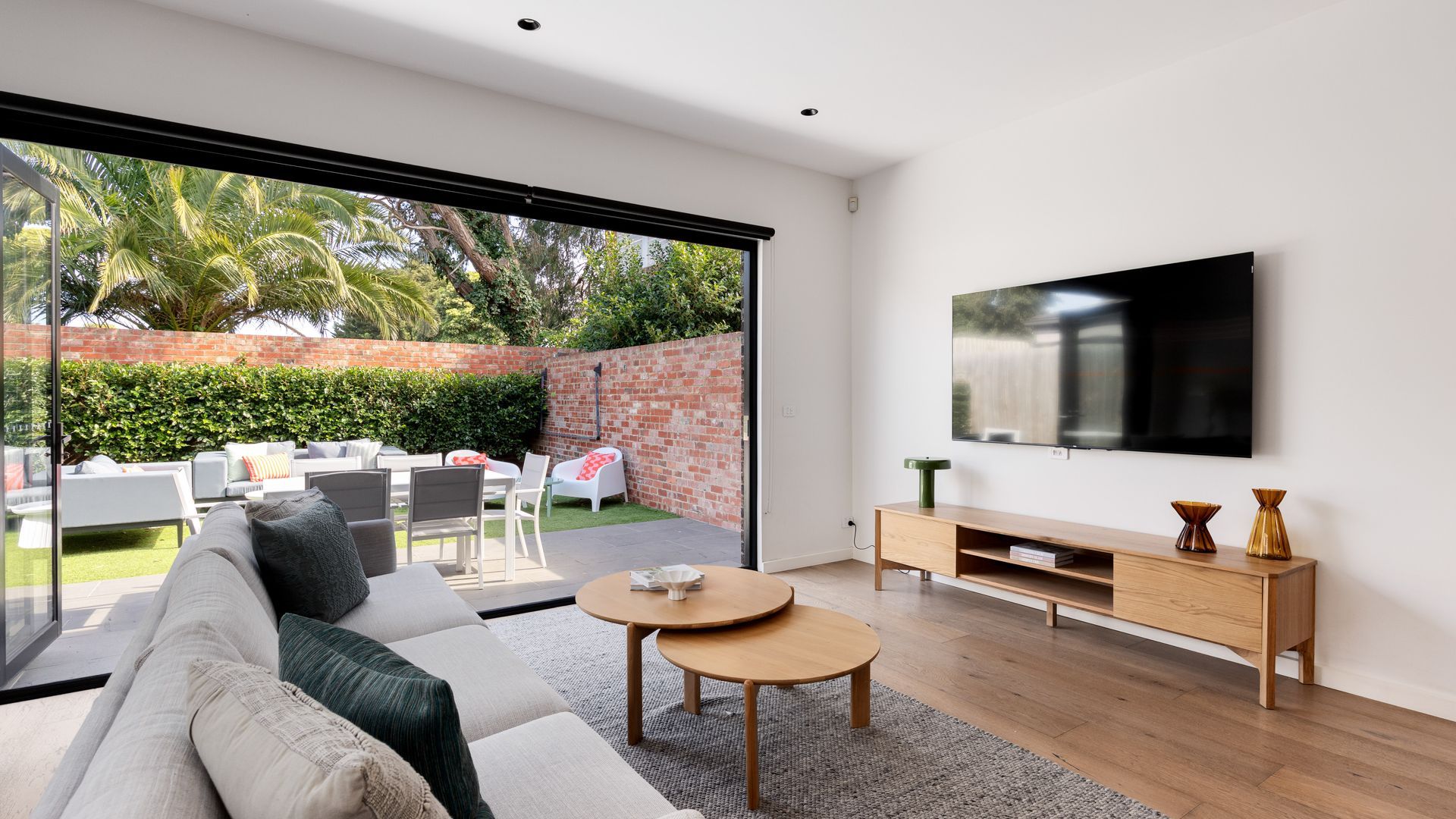 Una sala de estar moderna con un amplio ventanal corredera que da a un patio exterior.