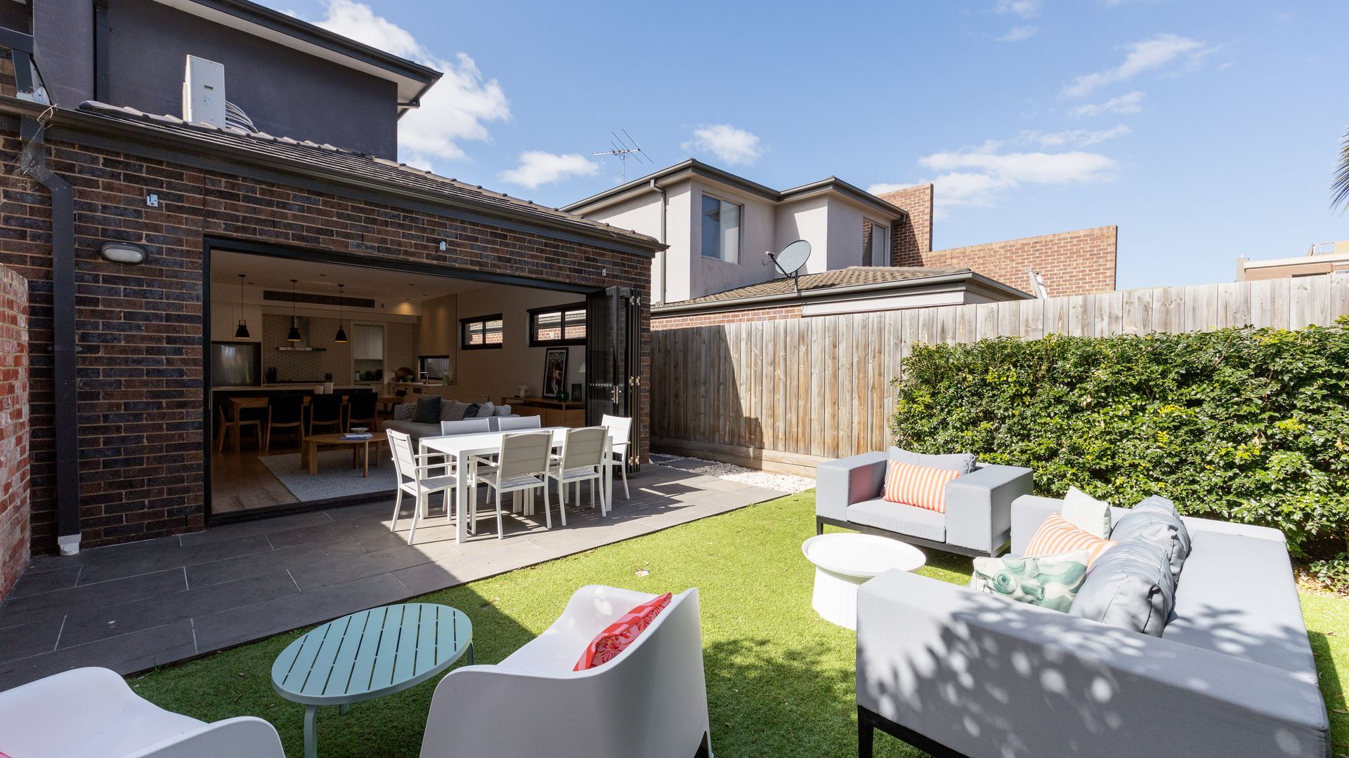 A residential backyard with a patio, outdoor seating, and a wooden fence.