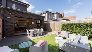 A residential backyard with a patio, outdoor seating, and a wooden fence.