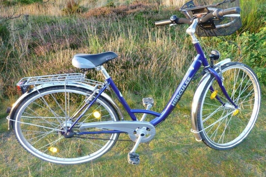A stationary bicycle with a basket and a seat, positioned outdoors.