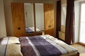 A bedroom with a bed, a wardrobe, and a window with curtains. - Holiday apartment with 1 bedroom (Cuxhaven-Sahlenburg)