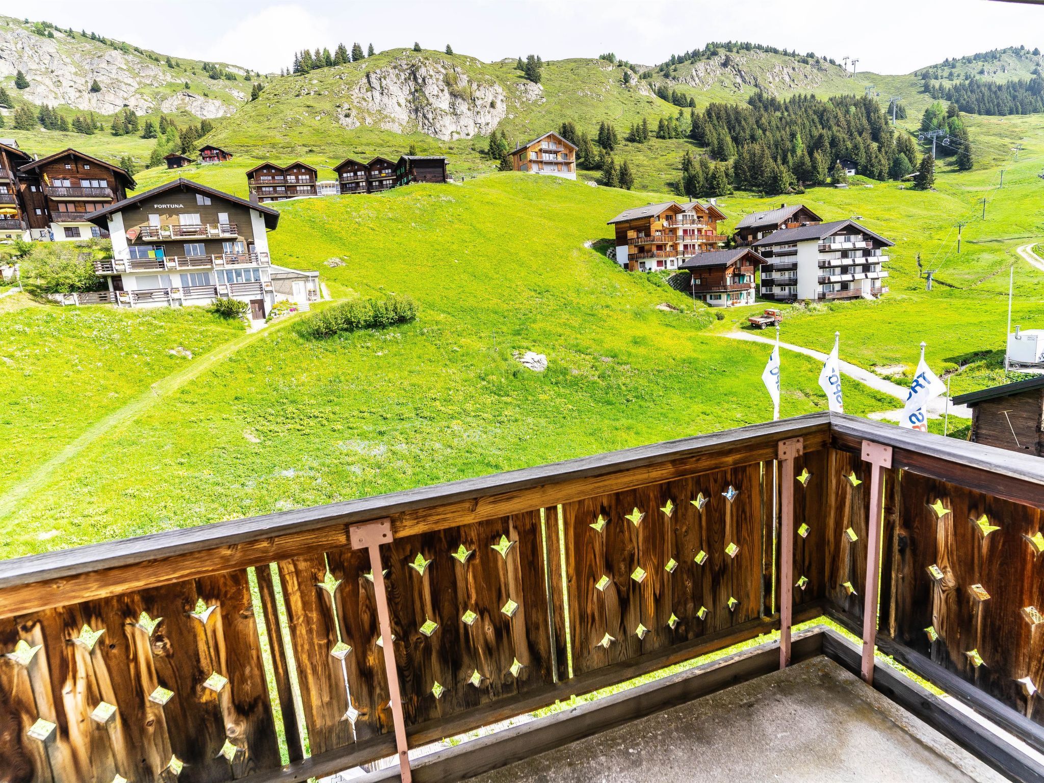 Une station de montagne avec des chalets en bois, un télésiège et une vue dégagée sur les collines environnantes.