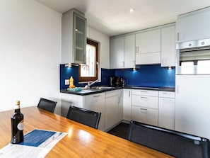 A compact kitchen with a dining table, chairs, and a built-in oven. - Sportina 33 3. OG Süd-West Appartement/Fewo, Dusche und Bad, WC by Interhome (Riederalp)