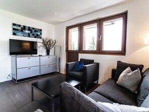 A modern living room with a flat-screen TV, a sofa, a coffee table, and a cabinet. - Sportina 33 3. OG Süd-West Appartement/Fewo, Dusche und Bad, WC by Interhome (Riederalp)