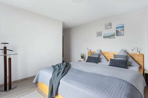 A bedroom with a bed, bedside tables, a wall-mounted lamp, and artwork. - Penthouse on the Baltic Sea (Kappeln)