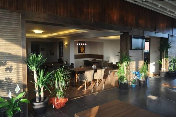 A spacious indoor area with a dining table and chairs, surrounded by potted plants. - Hotel Atabay (Istanbul)