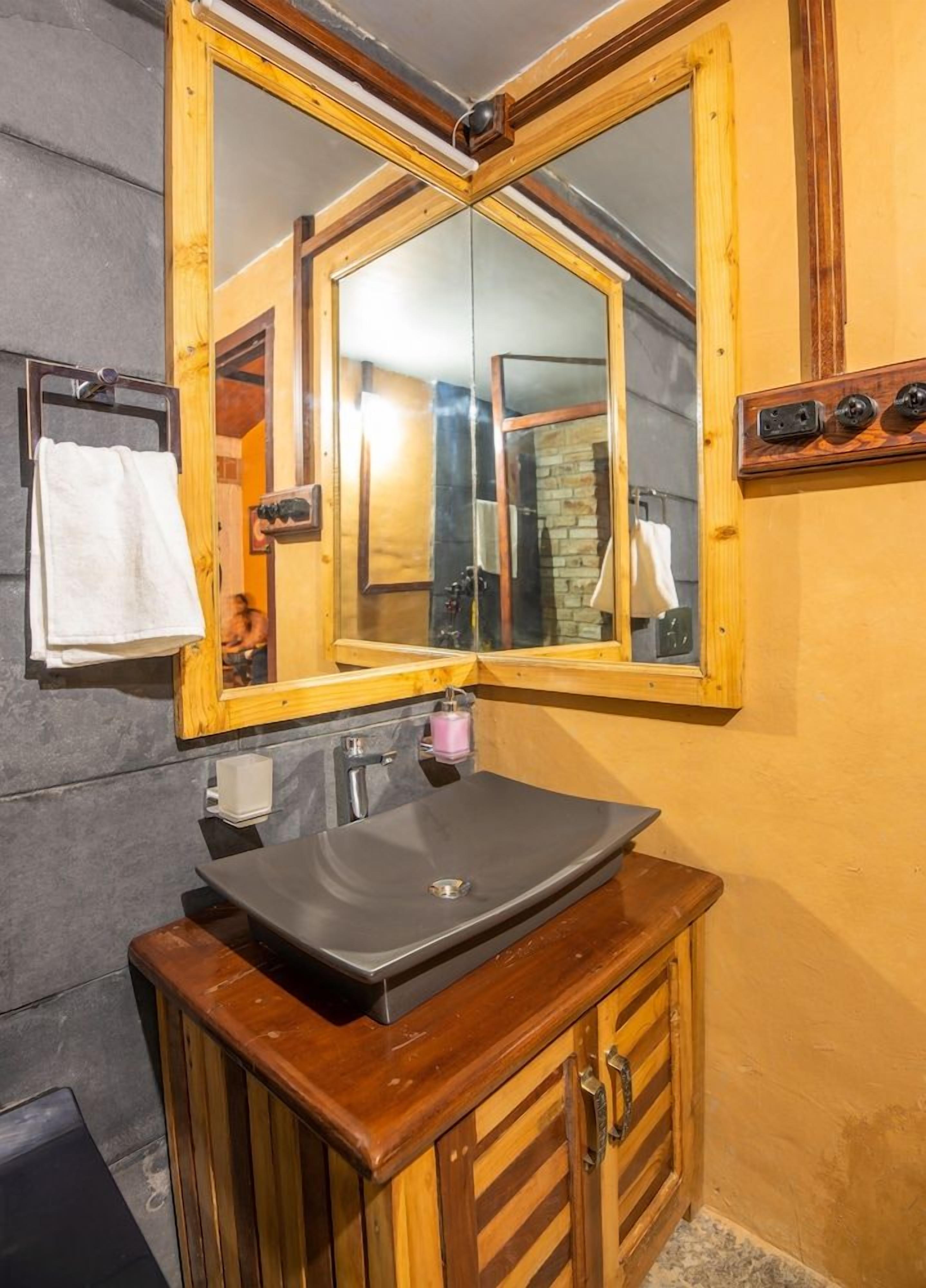 A bathroom with a wooden vanity, a large mirror, and a modern sink.