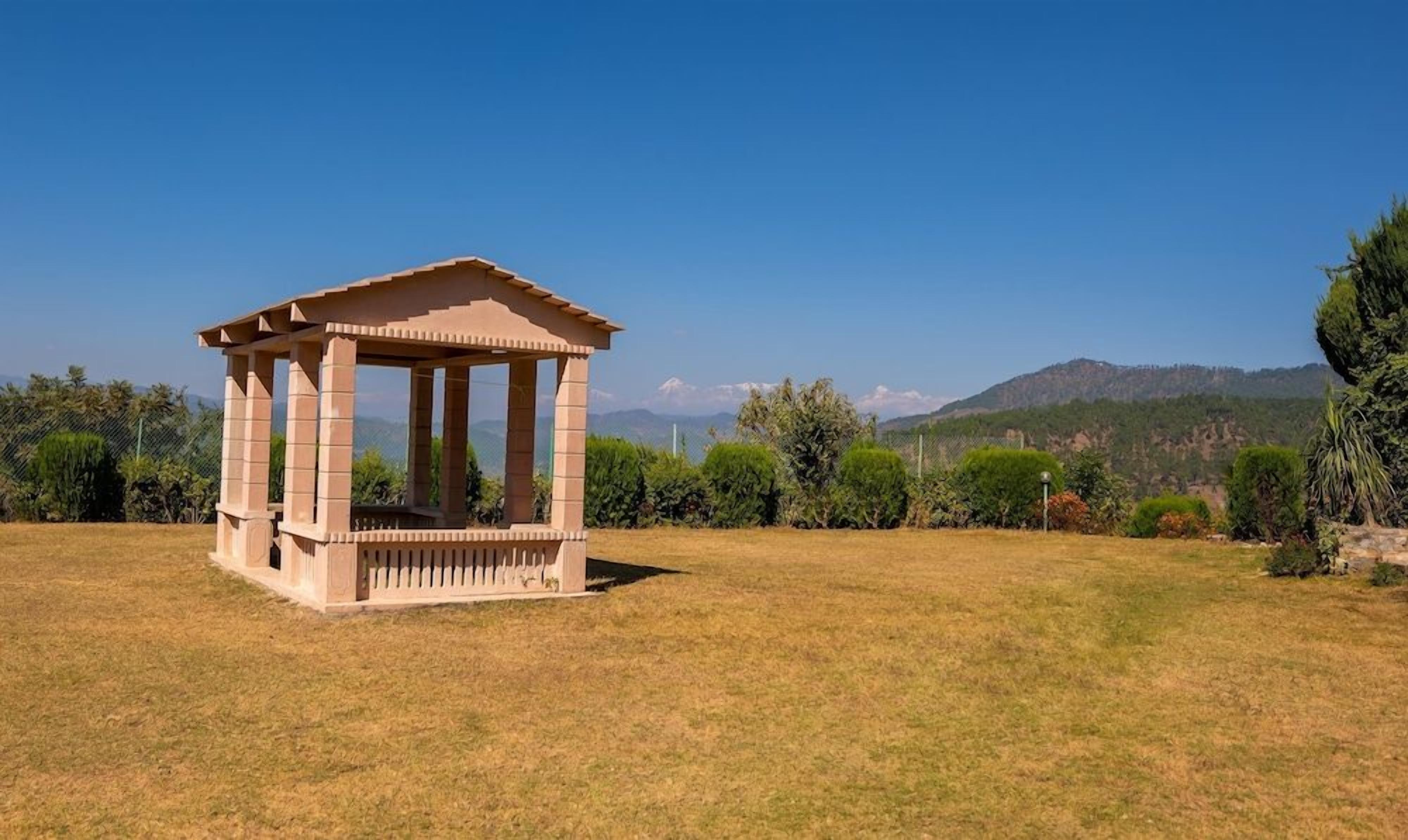 Un porxo de pedra en un camp d'herba amb una muntanya de fons.