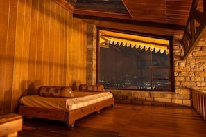 Um quarto acolhedor com uma cama, janela e vista para a cidade, além de paredes de madeira.