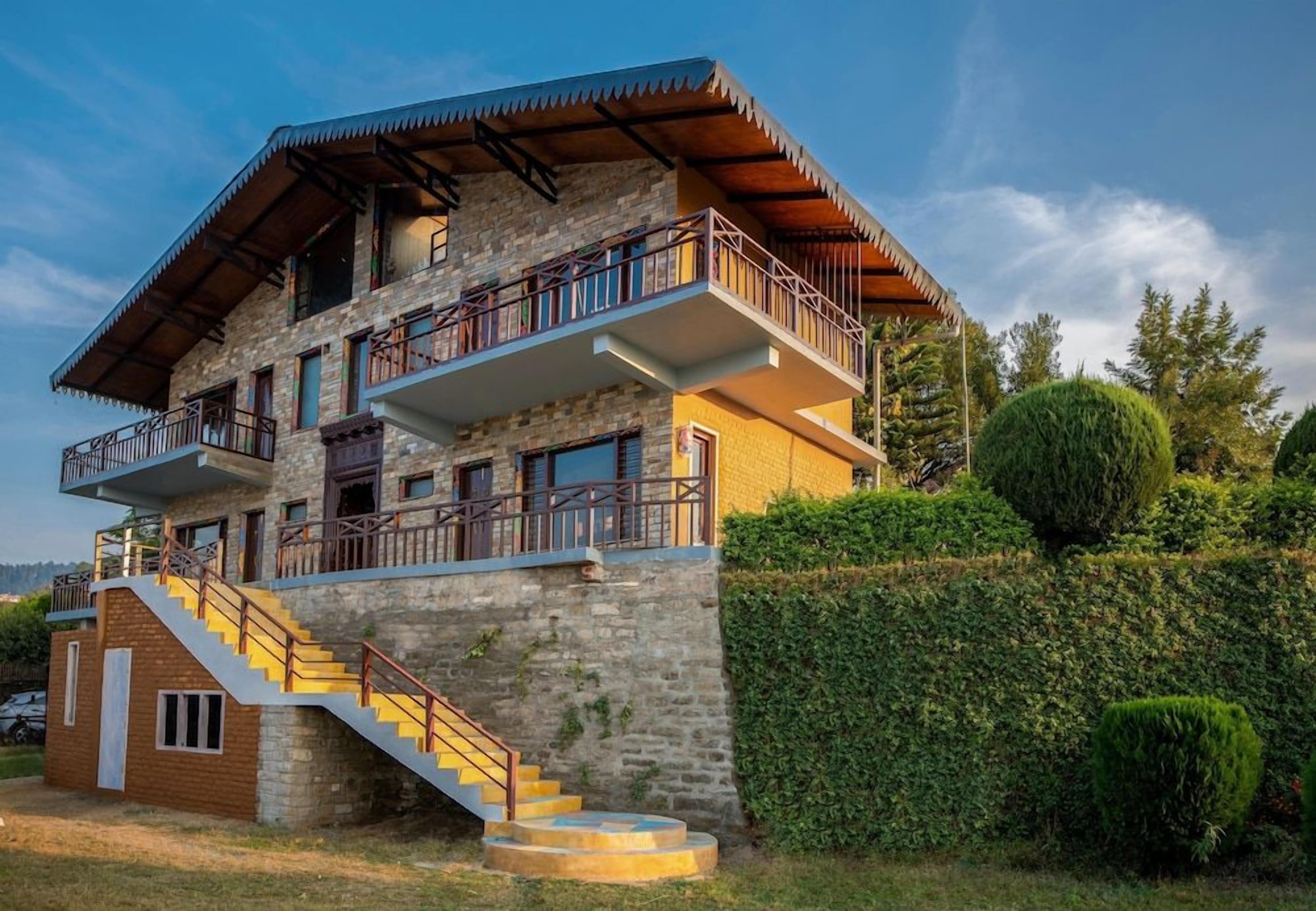 A multi-story building with a stone facade, a balcony on the upper floor, and a staircase leading to the entrance.