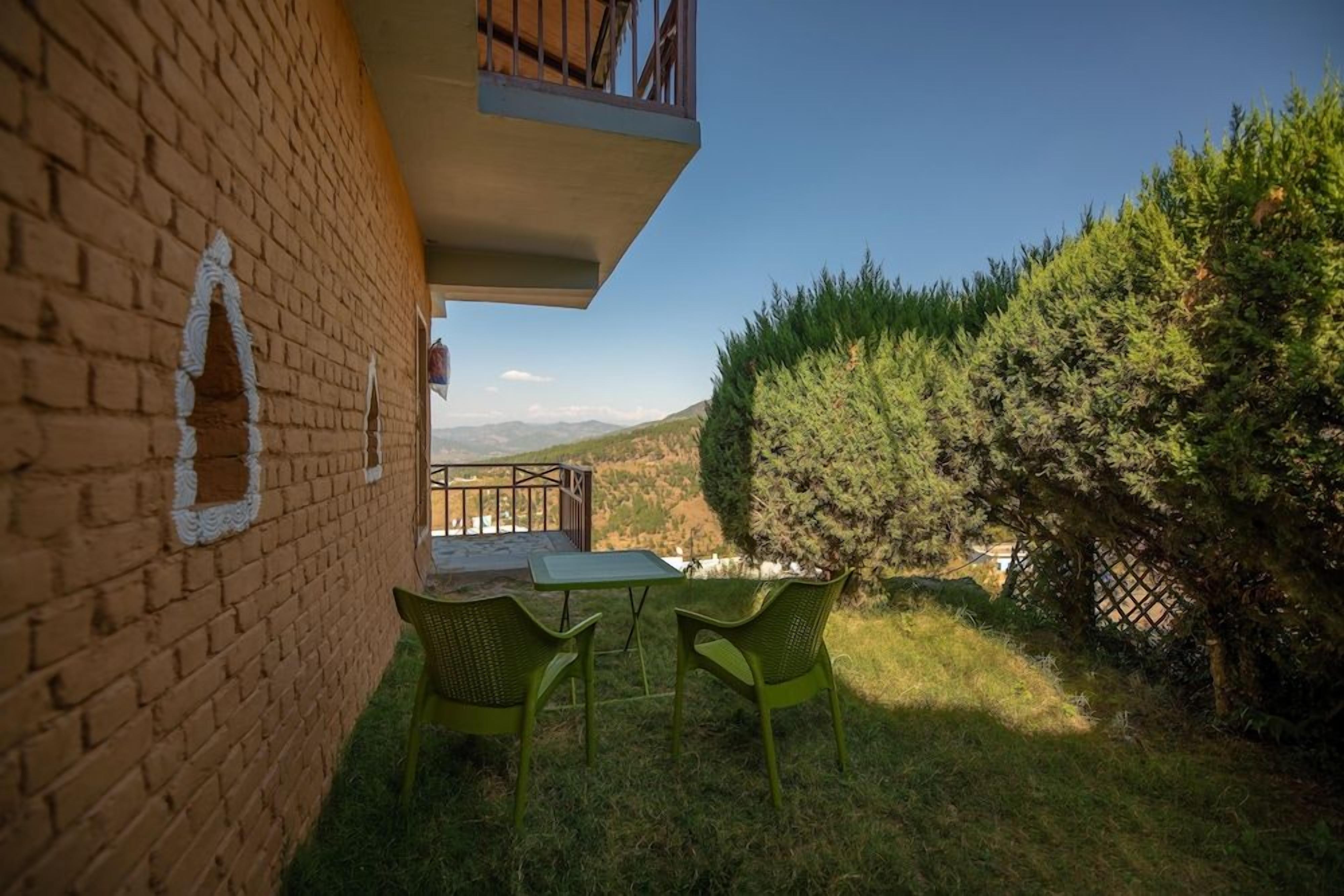 A patio with a table and chairs, a brick wall, and a view of the countryside.