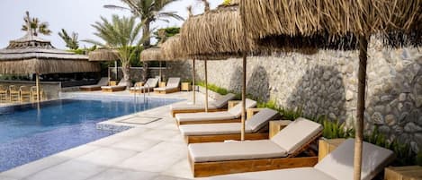 A poolside area with lounge chairs and thatched umbrellas.