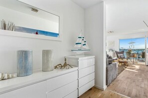 A modern living room with a white console table, a decorative sailboat, and a view of the sea through a large window. - Holiday apartment with 2 bedrooms (Kappeln)